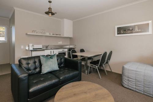 a living room with a leather couch and a table at South Street West Motel in Feilding