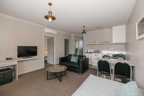 a living room with a couch and a table with a television at South Street West Motel in Feilding