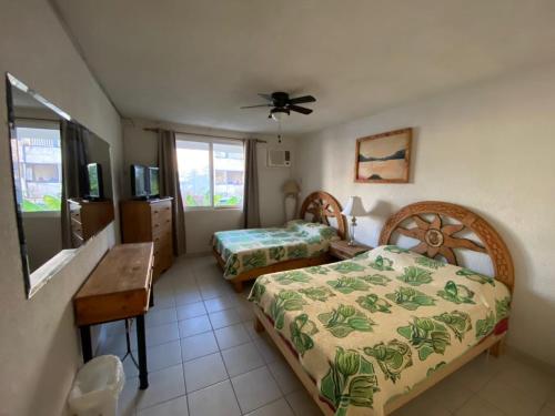 a bedroom with two beds and a desk and a tv at CONDOMINIO SÁBALO VISTA in Mazatlán