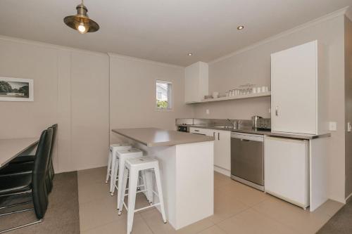 a kitchen with white walls and a counter with stools at South Street West Motel in Feilding