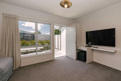 a bedroom with a large window and a flat screen tv at South Street West Motel in Feilding
