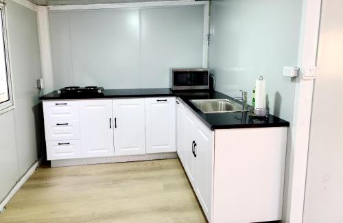 eine weiße Küche mit einer Spüle und einer Mikrowelle in der Unterkunft Independent guest unit with separate entry in Chilliwack