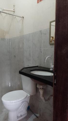a bathroom with a white toilet and a sink at Casa - suites com varanda in Conde