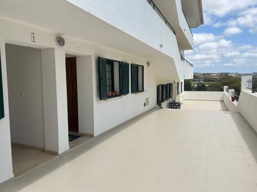 einen Balkon eines Hauses mit weißen Wänden und Fenstern in der Unterkunft Coast Beach Apartment - Praia da Areia Branca in Praia da Areia Branca