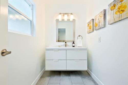 uma casa de banho branca com um lavatório e um espelho em La Jolla Beach Retreat Compound em San Diego