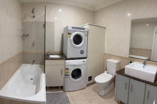 uma casa de banho com uma máquina de lavar roupa e um WC em 2 Bedroom Apartment @ Grenfell Street em Adelaide