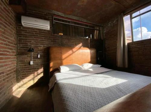 a bedroom with a bed and a brick wall at Loft DT con mesa de billar in Tijuana