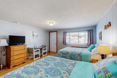 a bedroom with two beds and a desk and a television at Coastal Calm Studio Cottages in Wells