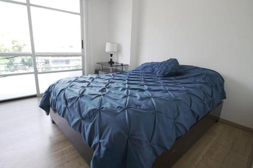 Una cama con un edredón azul en un dormitorio. en Great location, nice apartment Polanco, en Ciudad de México
