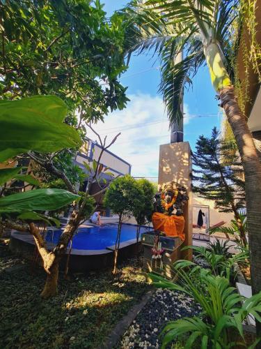 un barco en un jardín con palmeras en Ratu Guest House en Kuta