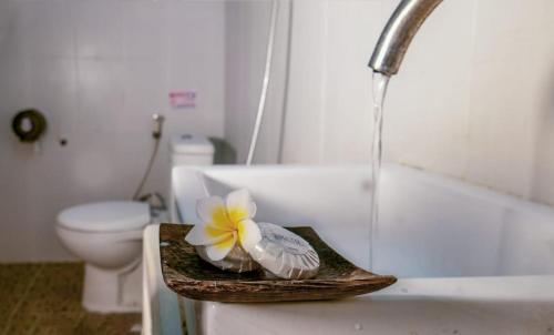uma casa de banho com um WC e um lavatório com uma flor em Ratu Guest House em Kuta