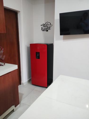 a red refrigerator in a room with a tv at Departamento México in Tampico