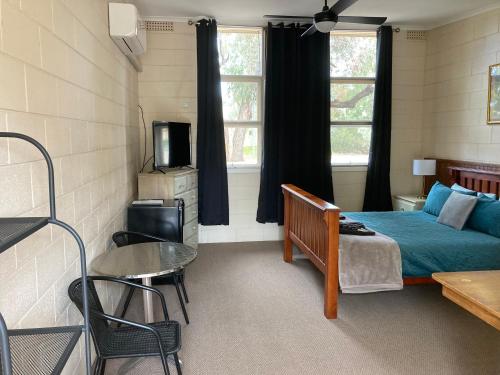 1 dormitorio con 1 cama, mesa y sillas en Flinders Ranges Motel - The Mill, en Quorn