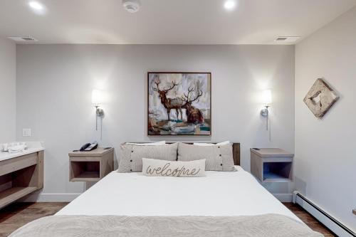 a bedroom with a large white bed and a painting on the wall at Lion Square Lodge South 261 in Vail