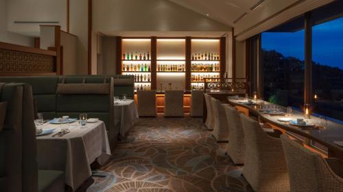 a restaurant with white tables and chairs and a bar at Izu Hotel Resort & Spa in Higashiizu