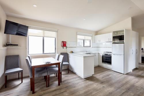 a kitchen with white appliances and a table and chairs at Anglesea Family Caravan Park in Anglesea