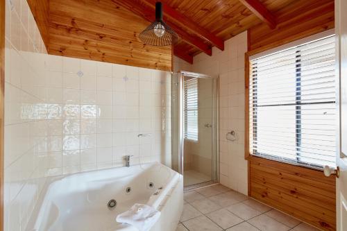 a bathroom with a tub and a shower and a window at Anglesea Family Caravan Park in Anglesea