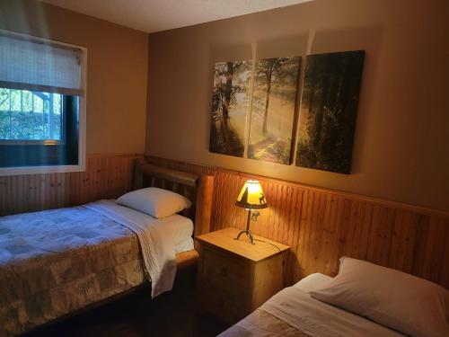 een slaapkamer met 2 bedden en een lamp op een tafel bij Riverbend Guest House in Chilliwack