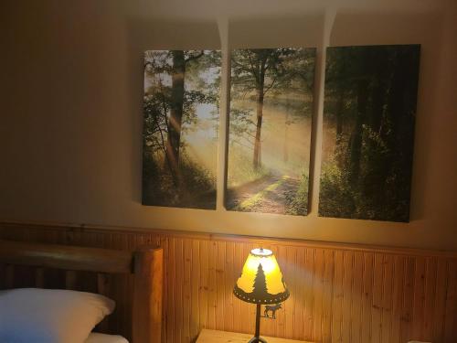 a lamp in a bedroom with three paintings on the wall at Riverbend Guest House in Chilliwack