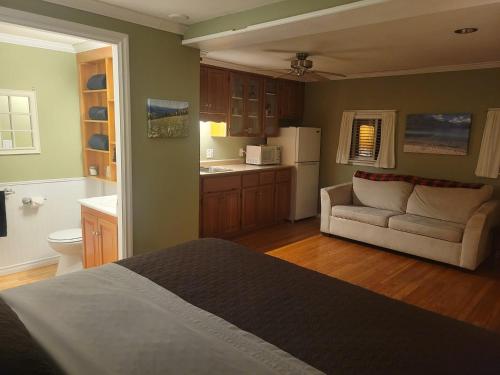 a bedroom with a bed and a couch and a kitchen at Riverbend Guest House in Chilliwack