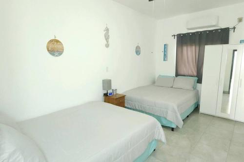 two beds in a room with white walls and white floors at Stay Here! 10 MIN FROM BEACH! 2 bedroom house in Puerto Peñasco