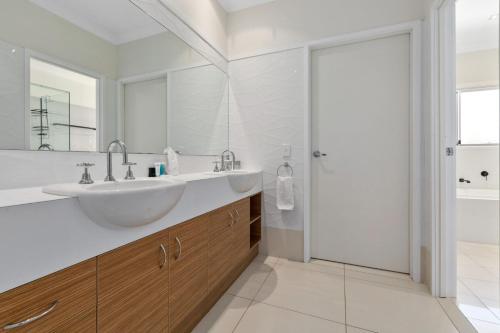 a white bathroom with a sink and a shower at Splash House at Kingscliff - Pet Friendly with Pool in Kingscliff