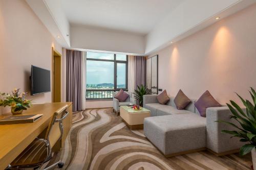 a living room with a couch and a tv at 佛山金美域林禧酒店 in Foshan