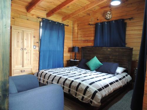 a bedroom with a bed and two blue chairs at Cabañas Big Mountain in Bernal