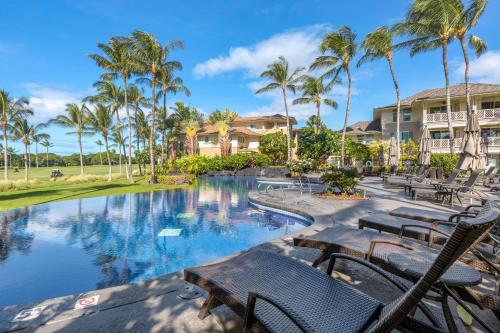 un complejo con piscina con sillas y palmeras en Fairway Villas Waikoloa by OUTRIGGER, en Waikoloa