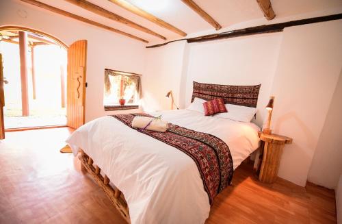a bedroom with a large bed with white sheets at Rumi Lodge Pisac in Pisac