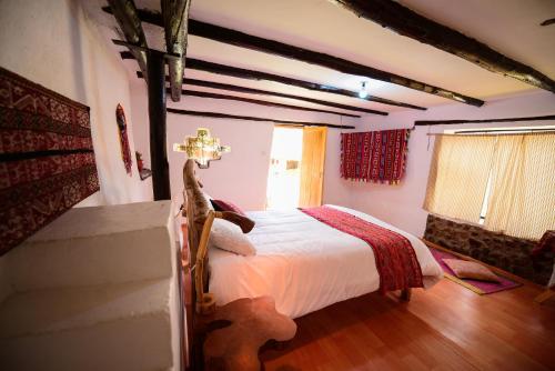 a bedroom with a bed in a room with wooden floors at Rumi Lodge Pisac in Pisac