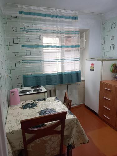 eine kleine Küche mit einem Tisch und einem Kühlschrank in der Unterkunft Аренда квартир Балхаш in Balqasch