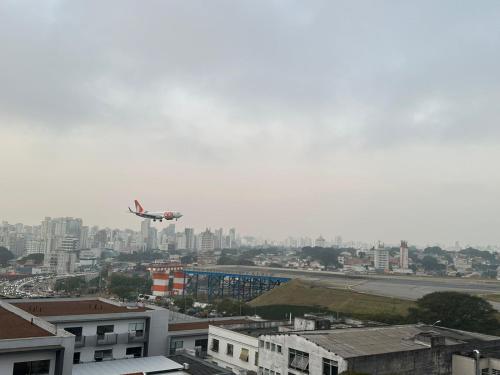 an airplane is flying over a city with buildings at Audaar Tech Suítes - Aeroporto de Congonhas in Sao Paulo