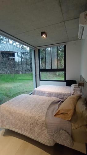 1 dormitorio con 2 camas y ventana grande en Aurora en Balneario Mar Azul