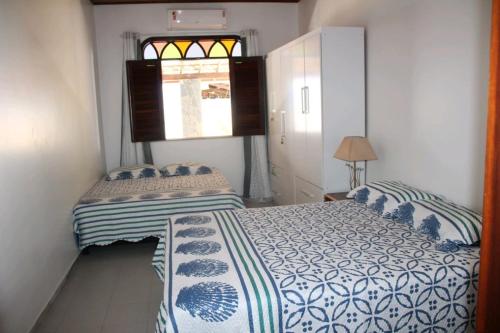 a bedroom with a bed with blue and white sheets and a window at Guarajuba Sereia House in Guarajuba