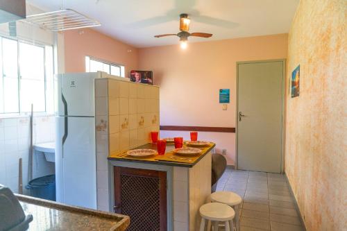 uma cozinha com um frigorífico e uma mesa com pratos em Apartamentos Incríveis Primeira Quadra Mar WiFi em Ubatuba