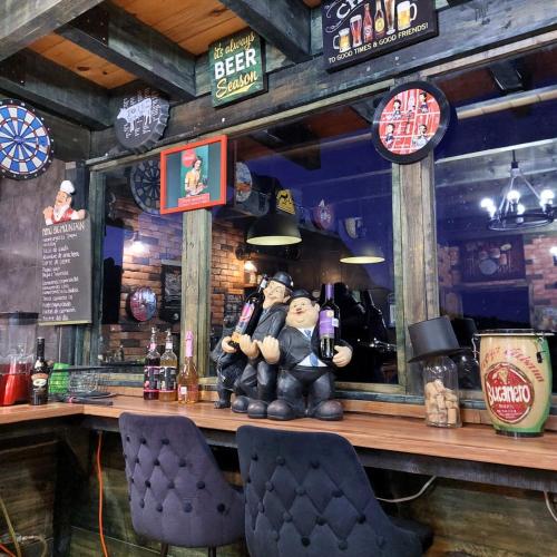 a bar with a statue of a man sitting at a counter at Cabañas Big Mountain in Bernal