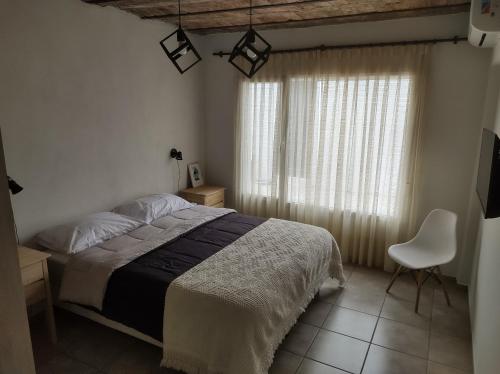 a bedroom with a bed and a chair and a window at Los Deptos de Alvear in Santa Rosa