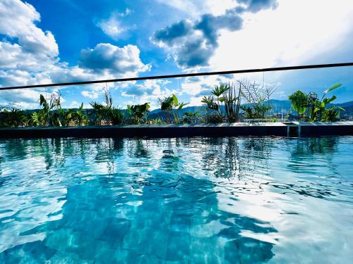 a swimming pool with blue water and a cloudy sky at Los Patios Cool Living in Medellín