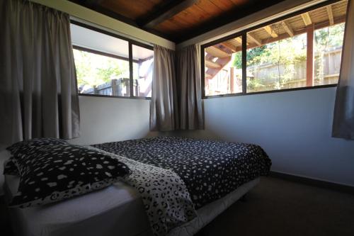 a small bedroom with a bed and two windows at 43b Conical Hill Road in Hanmer Springs