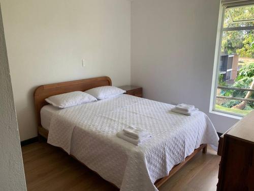 a bedroom with a bed with two towels on it at Hermosa casa de campo en ambiente tranquilo. in Rionegro