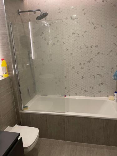 y baño con ducha, bañera y aseo. en Lovely bright, modern 1-bed apartment, en Londres
