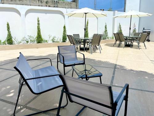 a group of chairs and tables and umbrellas on a patio at Exclusivo y amplio departamento 3 bedroom in Manta