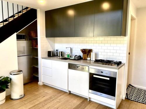 una cucina con armadi bianchi e piano cottura di Loft Style 1 bedroom Apartment a Sydney