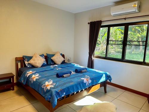 a bedroom with a bed with a blue comforter and a window at House of Garden Resort in Chiang Rai