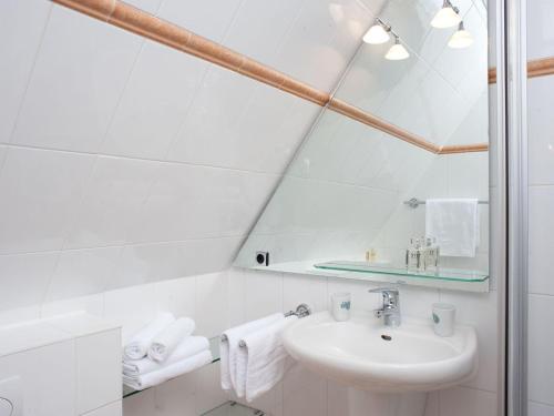 a white bathroom with a sink and a mirror at Spatzennest in Kampen