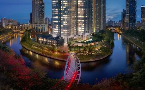 einem Fluss mit einem Riesenrad vor einer Stadt in der Unterkunft Fraser Residence River Promenade, Singapore in Singapur