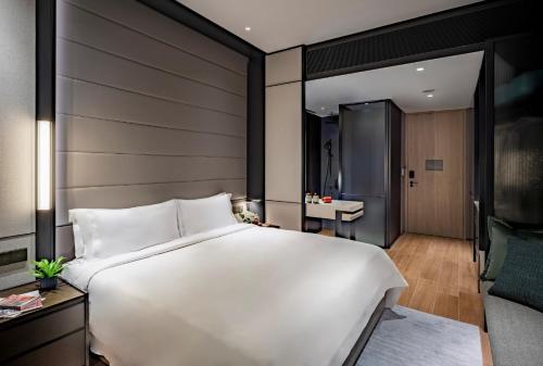 a bedroom with a large white bed and a bathroom at Fraser Residence River Promenade, Singapore in Singapore