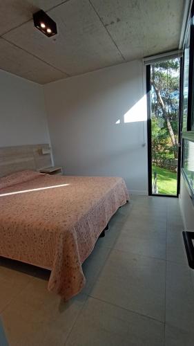 1 dormitorio con cama y ventana grande en Nereida en Balneario Mar Azul