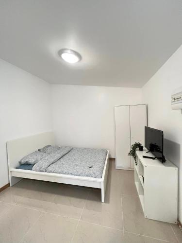 a white bedroom with a bed and a television at Gagny super studio très calme in Gagny